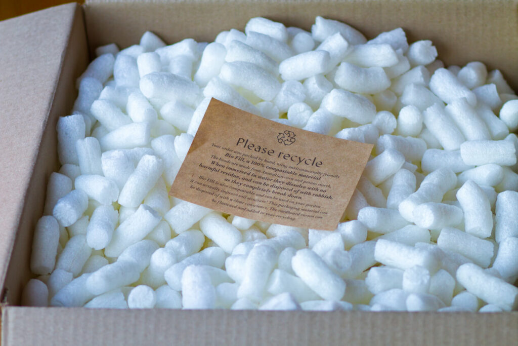 Recyclable packing peanuts with instructions with a note that says please recycle.